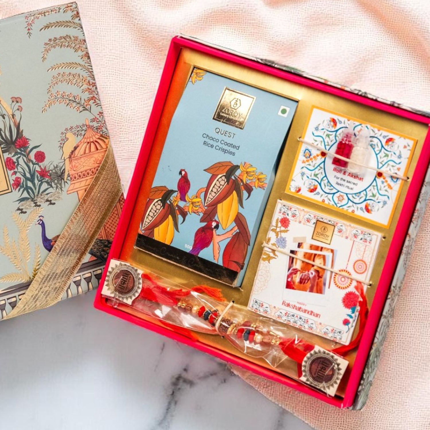 ZOROY Rakhi Gift Kit | Compact Raksha Bandhan Hamper with Quest Choco Rice Crisps, 2 Rakhis, Akshat Kumkum, Rakhi Card | Essentials-Only Rakhi Gift Box for Brother, Bhabhi, Kids & Family