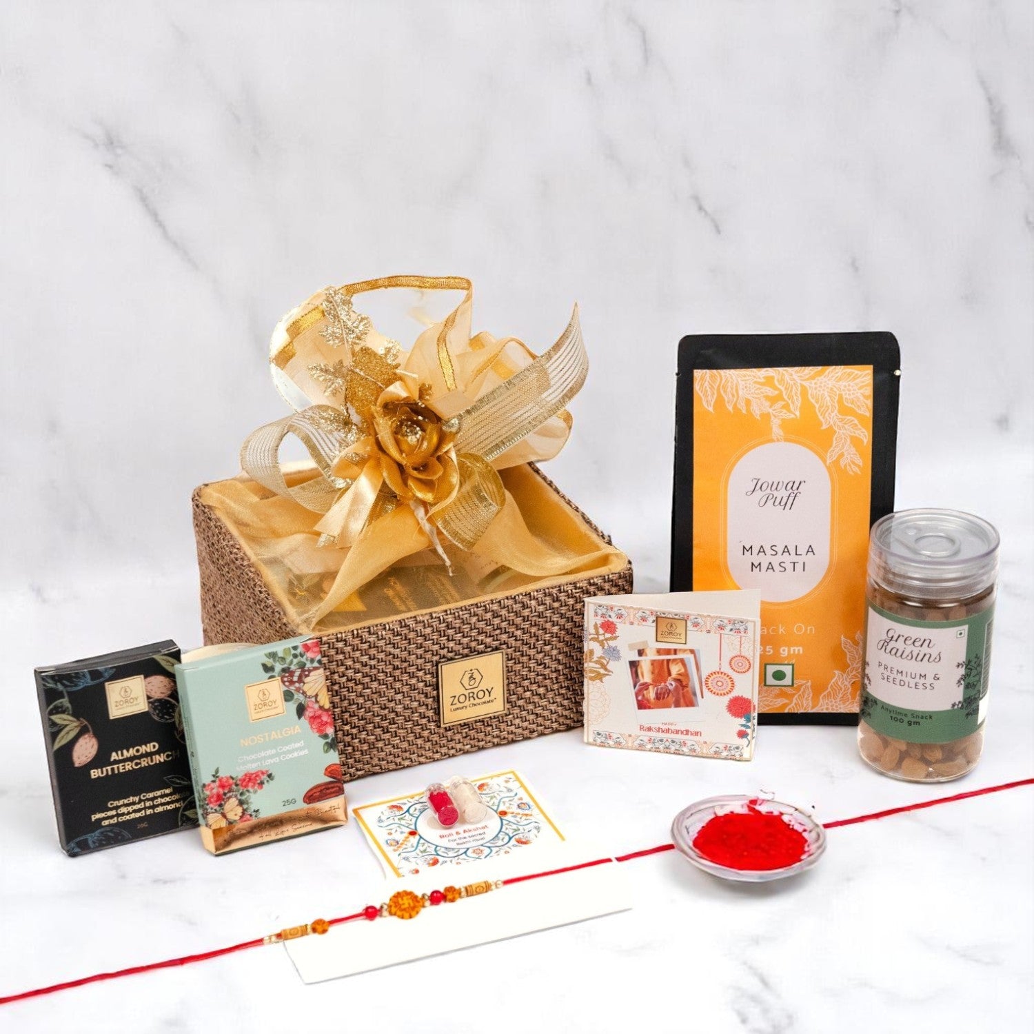 ZOROY Raksha Bandhan Organza  Gift Hamper with Rakhi, Akshat Kumkum, Rakhi Card, Chocolate Lava Cookie, Buttercrunch Snack, Raisins 100g  – Rakhi Gift for Brother, Bhai, Sibling