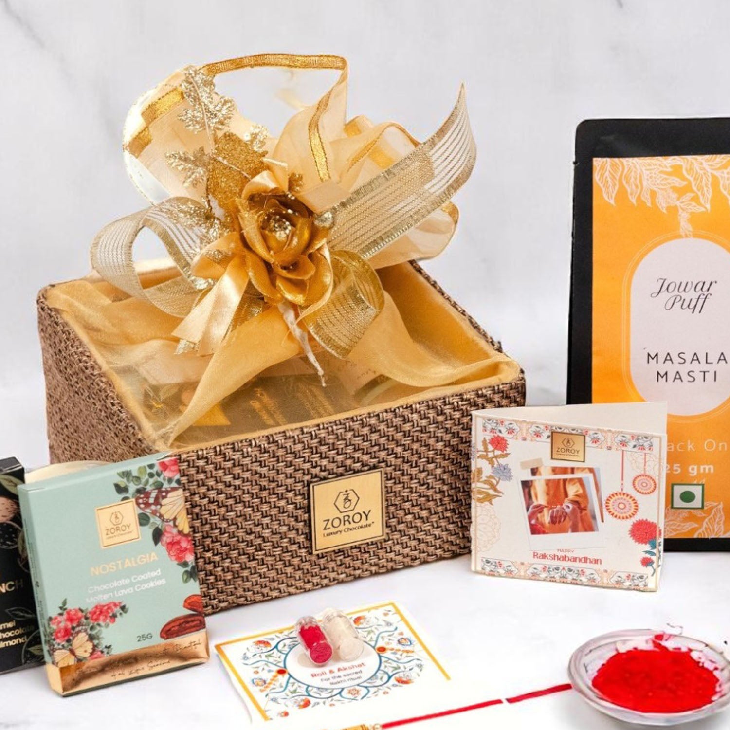 ZOROY Raksha Bandhan Organza  Gift Hamper with Rakhi, Akshat Kumkum, Rakhi Card, Chocolate Lava Cookie, Buttercrunch Snack, Raisins 100g  – Rakhi Gift for Brother, Bhai, Sibling