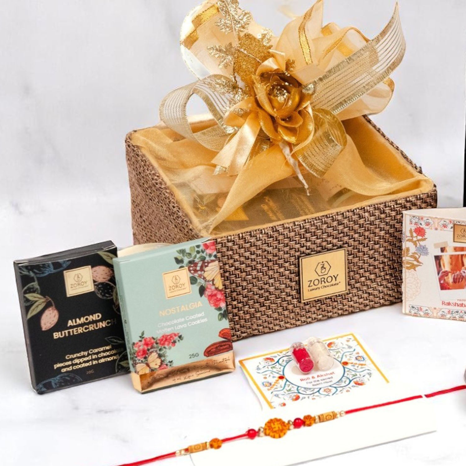 ZOROY Raksha Bandhan Organza  Gift Hamper with Rakhi, Akshat Kumkum, Rakhi Card, Chocolate Lava Cookie, Buttercrunch Snack, Raisins 100g  – Rakhi Gift for Brother, Bhai, Sibling